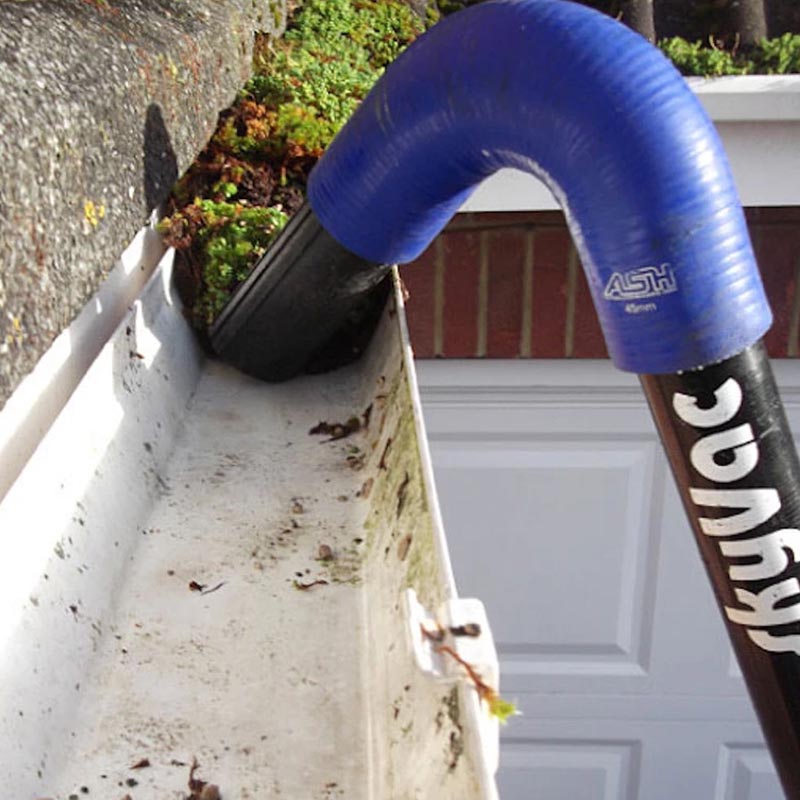 Gutter being cleared of debris using a high-reach gutter vacuum system